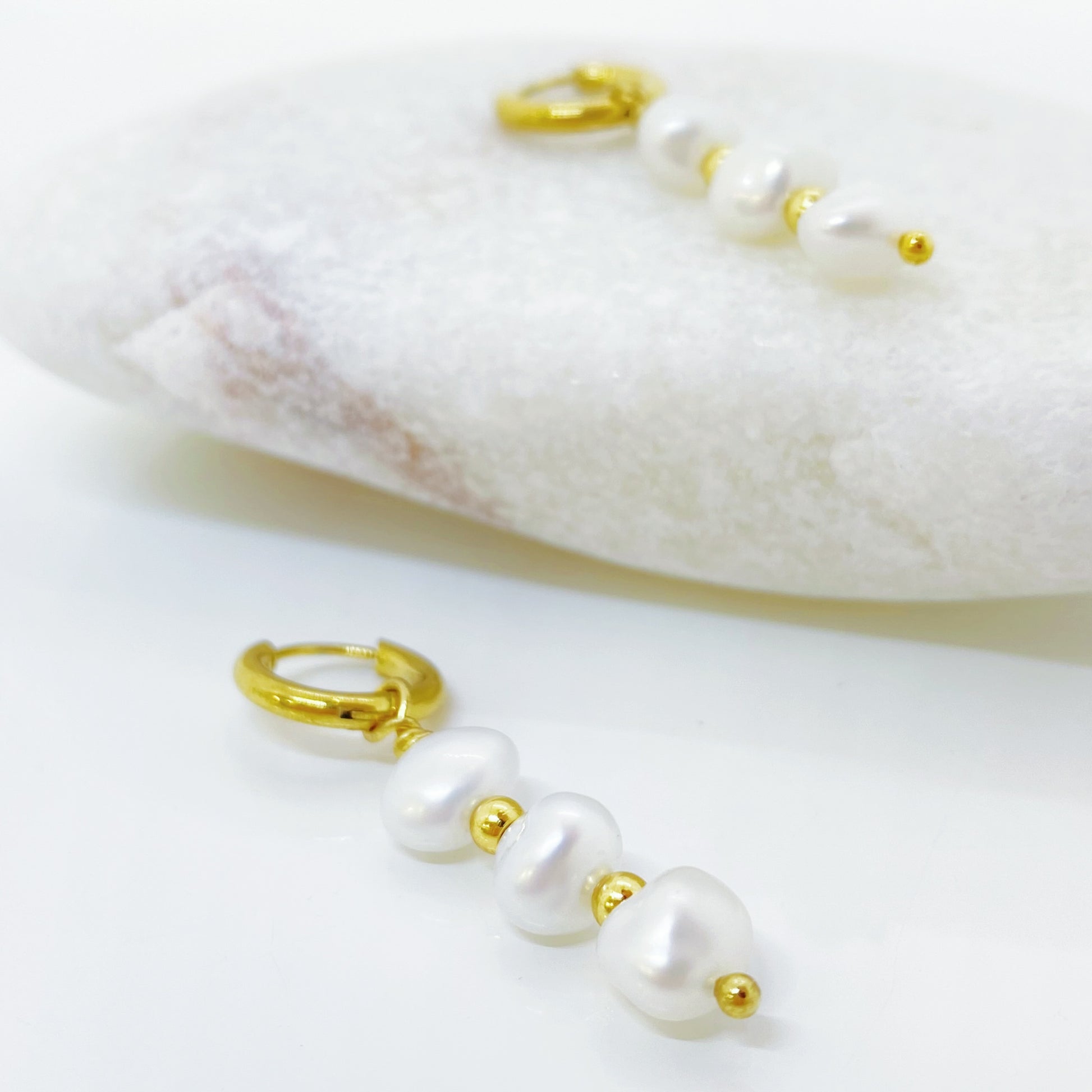 Brinco com três pérolas naturais e detalhes dourados. Joia delicada que transmite elegância, pureza e conexão com a essência feminina.